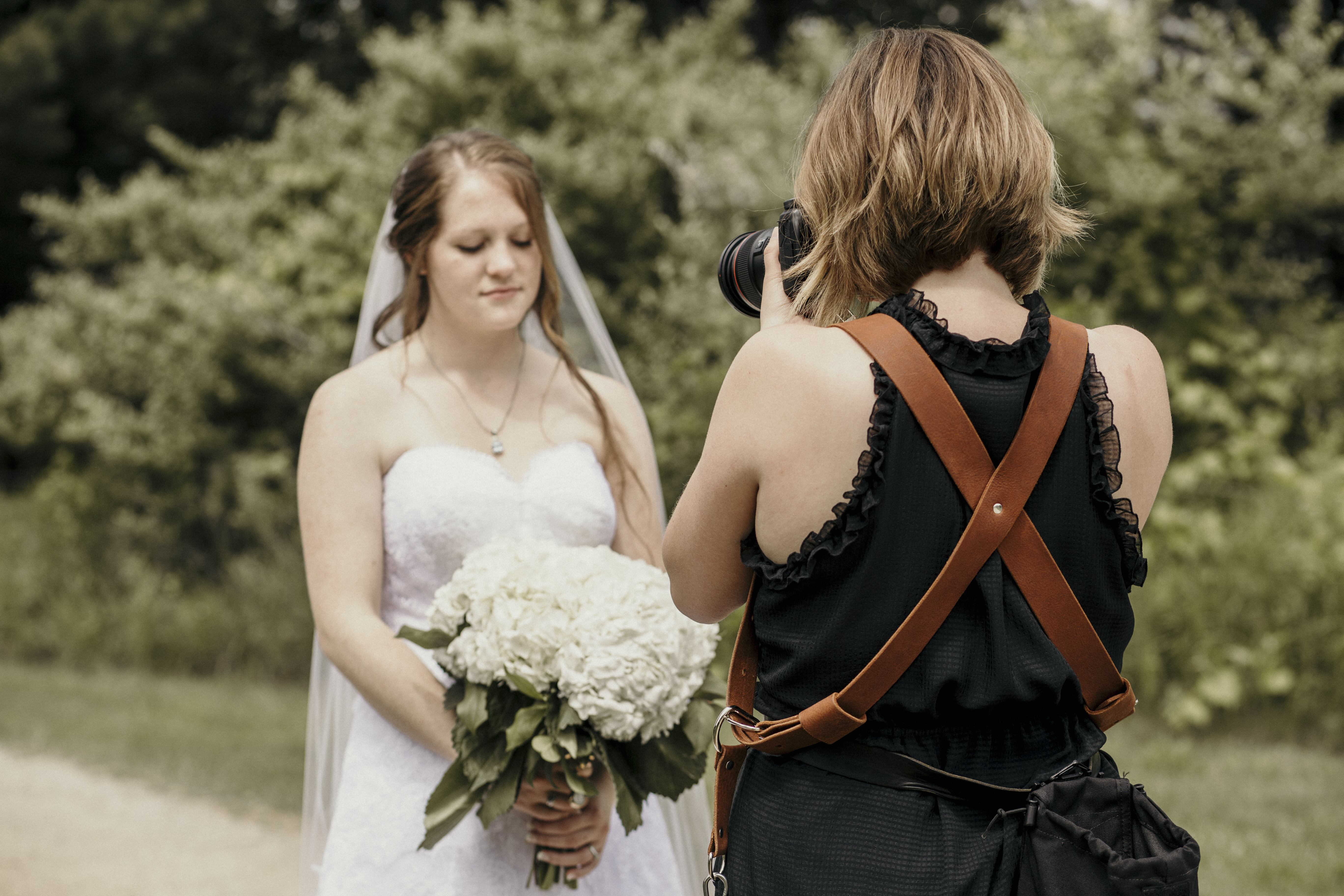 photographer taking photo of bride holding flowers